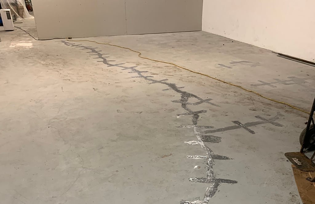 Concrete floor slab with a repaired crack line across the surface