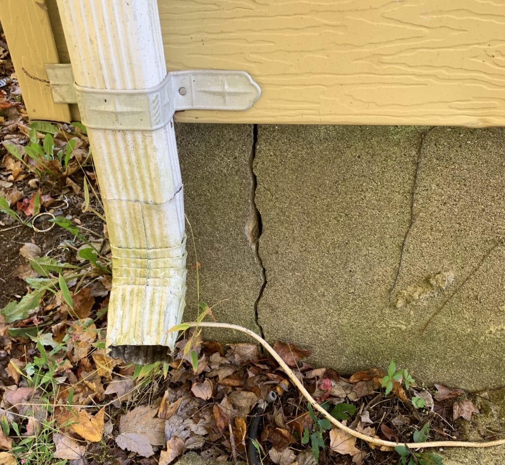 foundation crack visible next to water spout of home