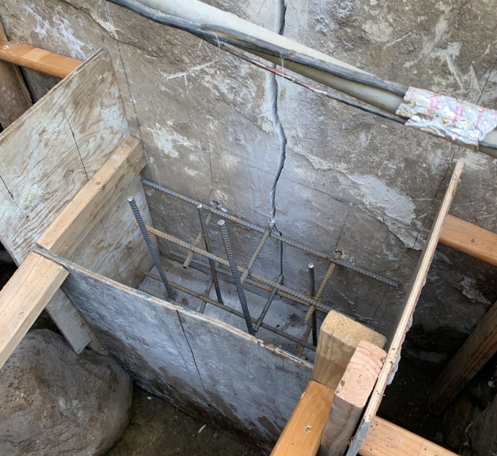 footer repair and reinforcement, foundation crack clearly visible with extensive construction work happening